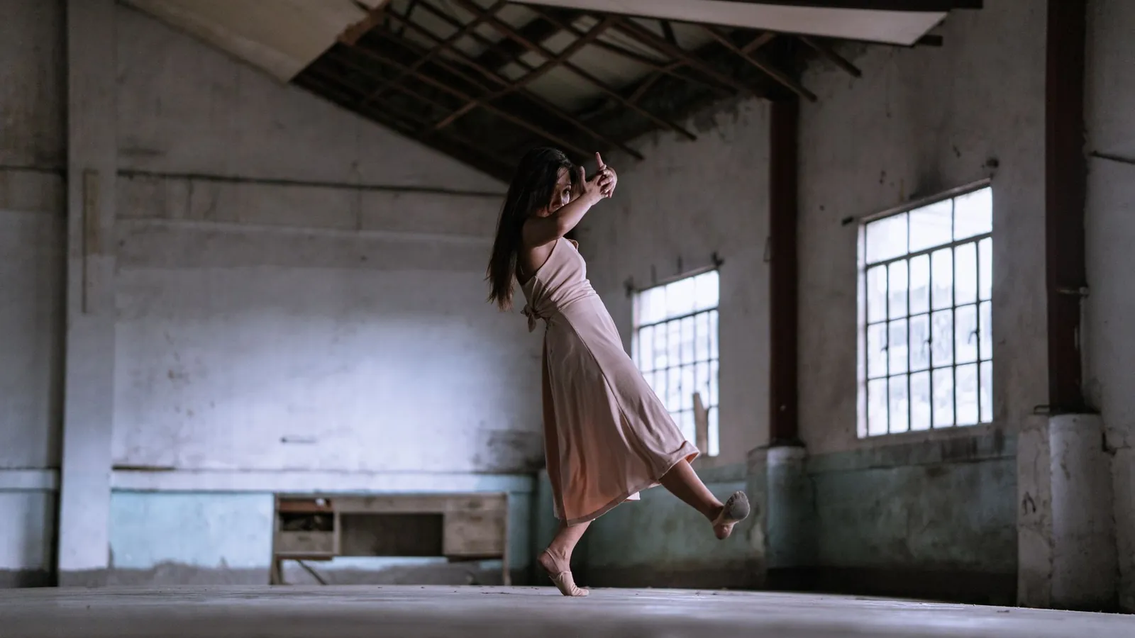 Bailarina en suspensión dentro de una sala de ensayo con ventanales altos