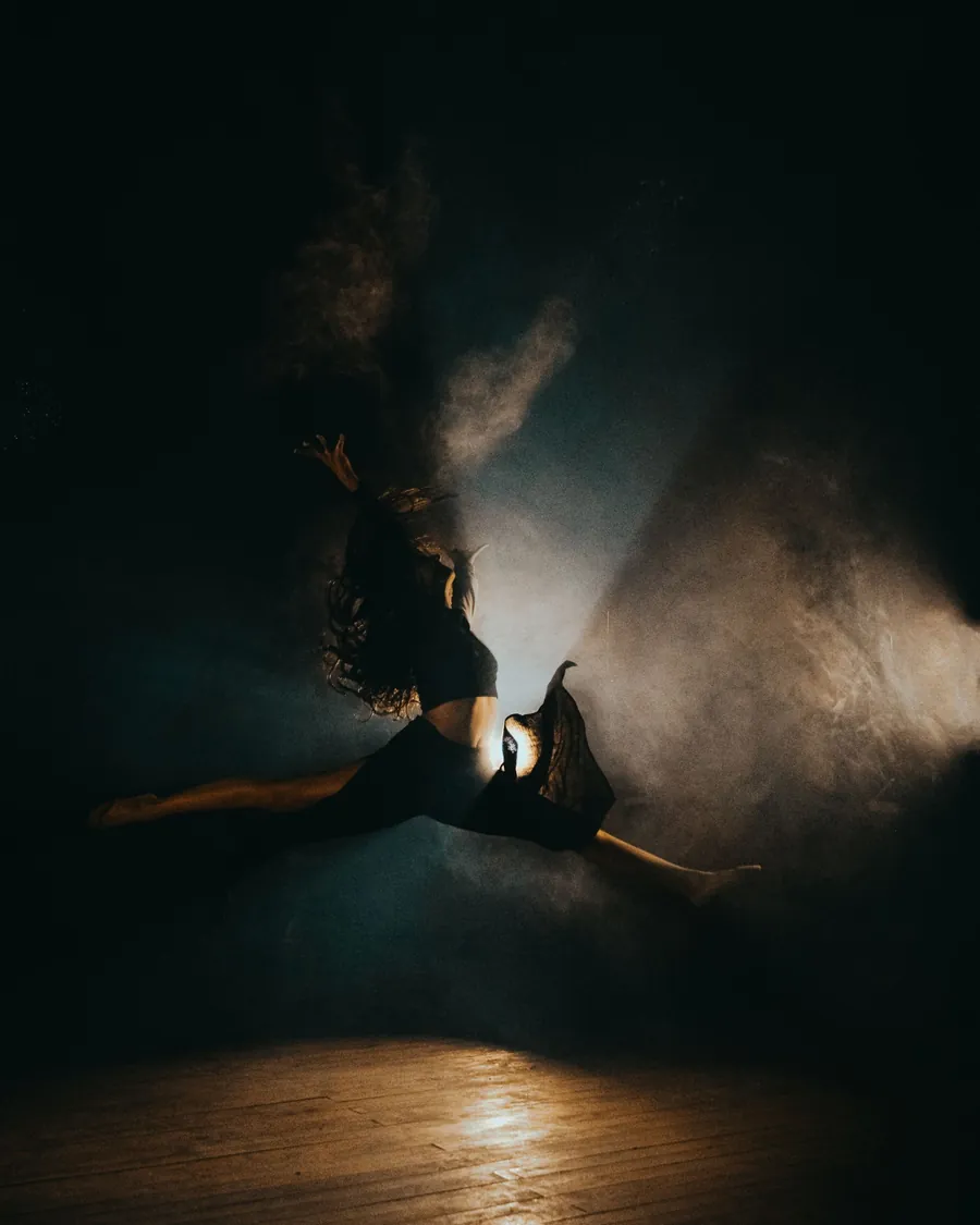 Bailarina contemporánea suspendida en el aire entre una nube de polvo