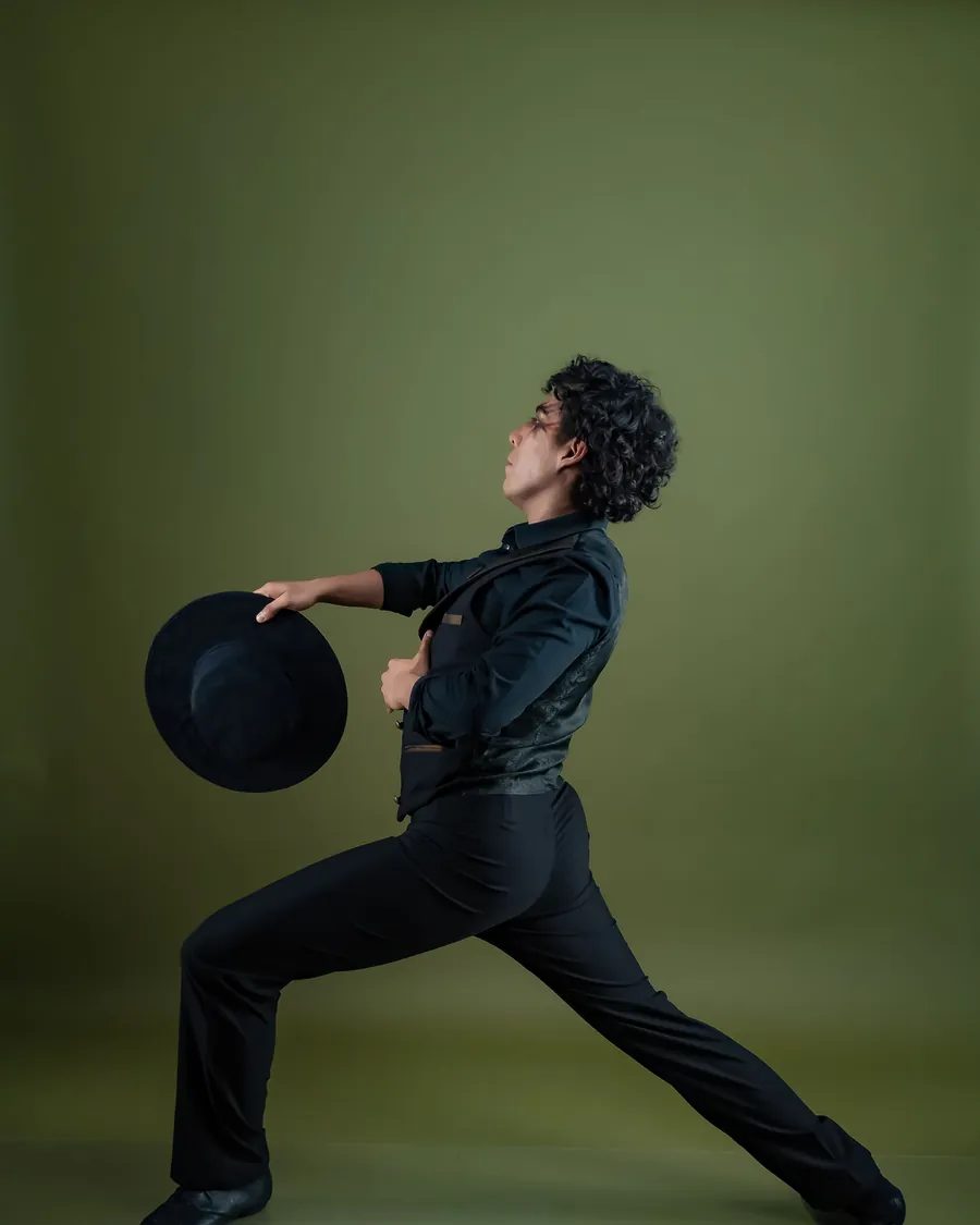 Bailarín de jazz con sombrero en posición de lunge sobre fondo verde
