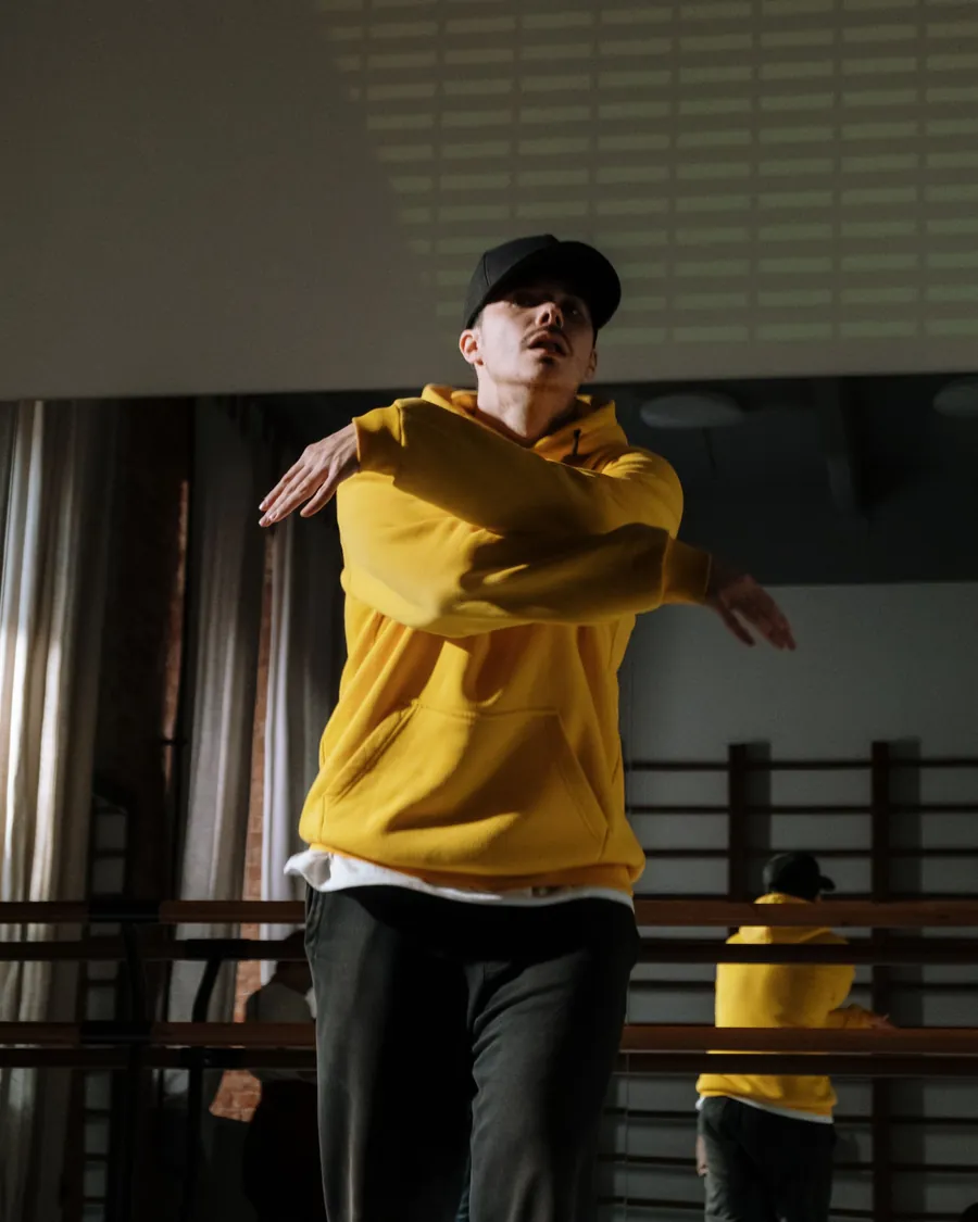 Bailarín urbano con buzo amarillo en movimiento dentro de la sala